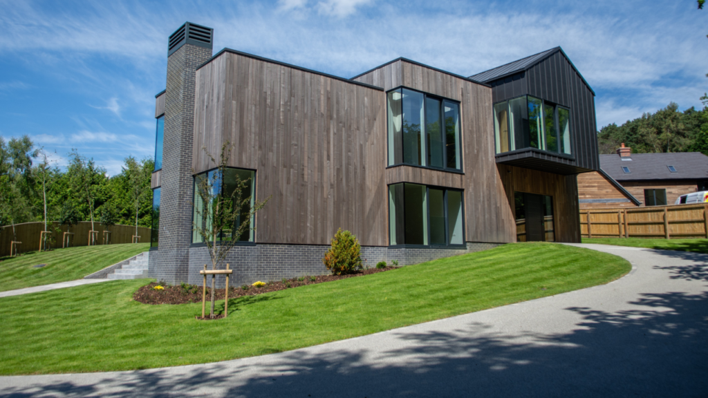 Modern timber frame home with timber cladding and landscaped lawn, showcasing quality residential design